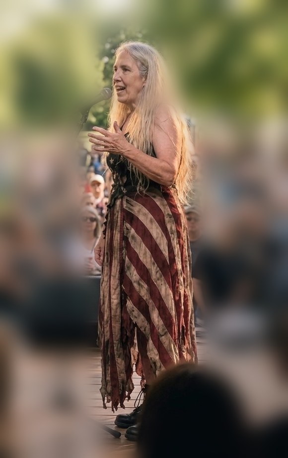 Izzy speaking on an outdoor stage to a crowd